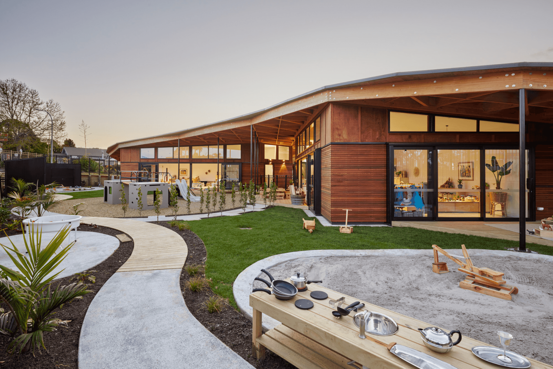 Wooden childcare centre with playground, sandpit, and sunset